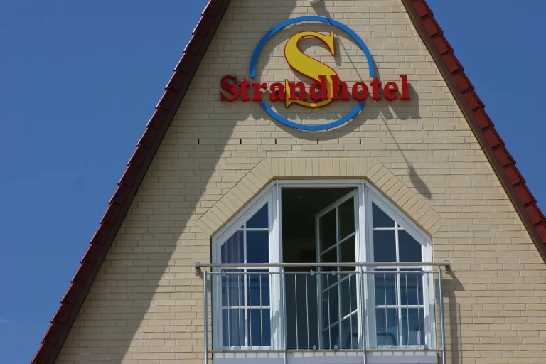 Giebel des Strandhotels Grömitz mit Schriftzug und Balkon vor blauem Himmel