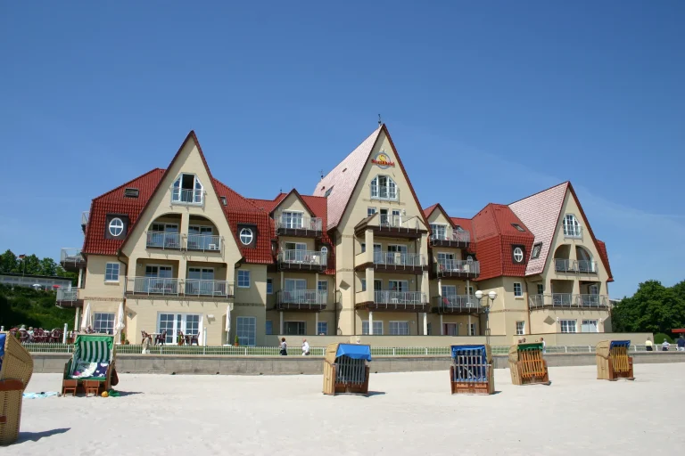 Strandhotel in Grömitz mit hellen Ziegelfassaden und roten Dächern, im Vordergrund Strandkörbe