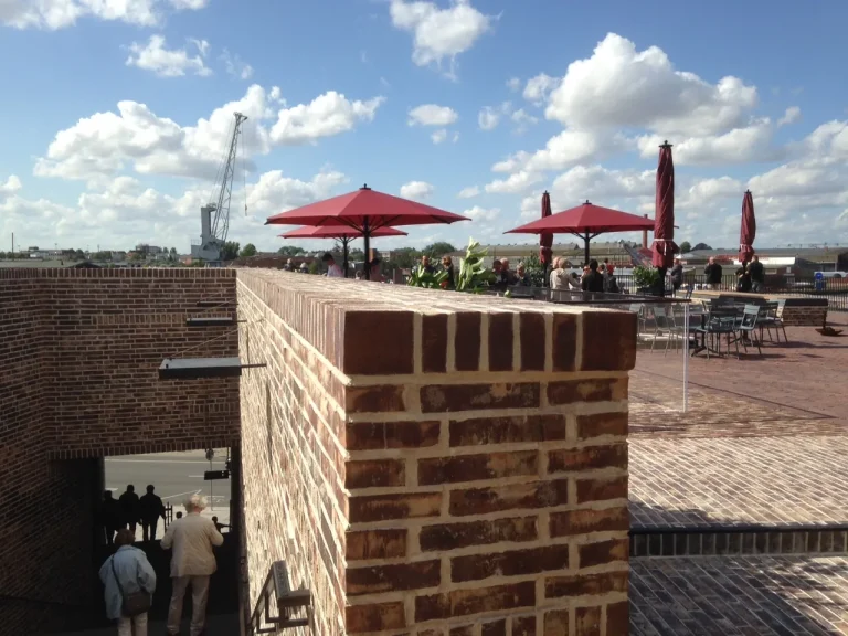 Ziegelmauer mit Ecke und roten Sonnenschirmen auf der Dachterrasse des Hanse-Museums