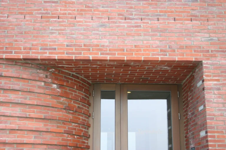 Tiefe Ziegellaibung um eine Glastür an der gerundeten Fassade des Golfhauses Budersand